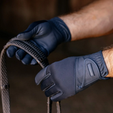 Close-up of hands wearing dark blue gloves holding a rubber rein.